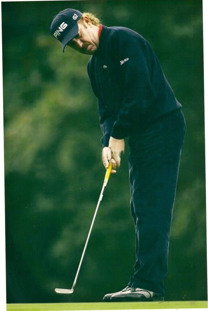 A man holding a golf club on top of a green.