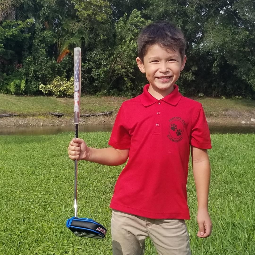 A young boy holding a golf club in his hand.