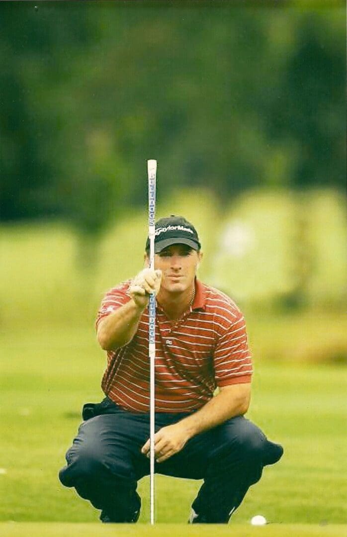 A man holding a golf club on the grass.