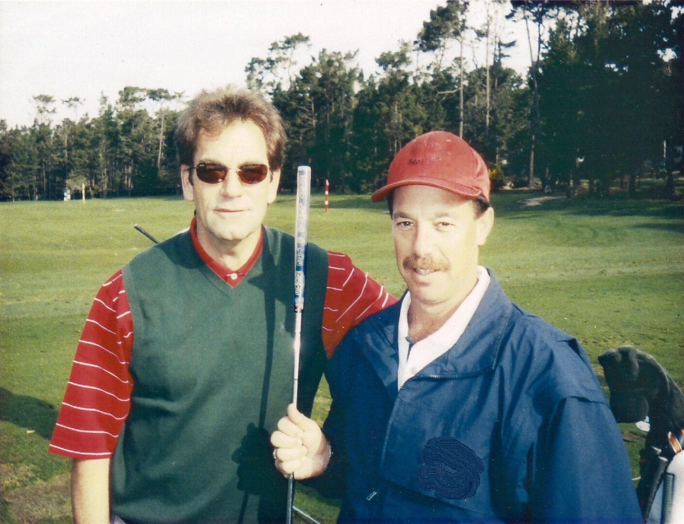 Two men standing next to each other holding a baseball bat.