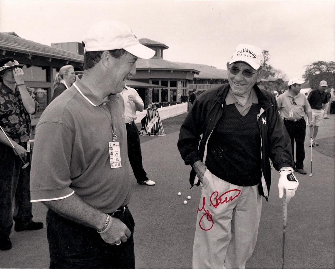 Two men talking to each other while holding golf clubs.