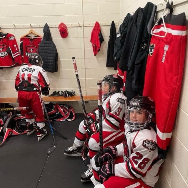 A group of hockey players sitting in the locker room.